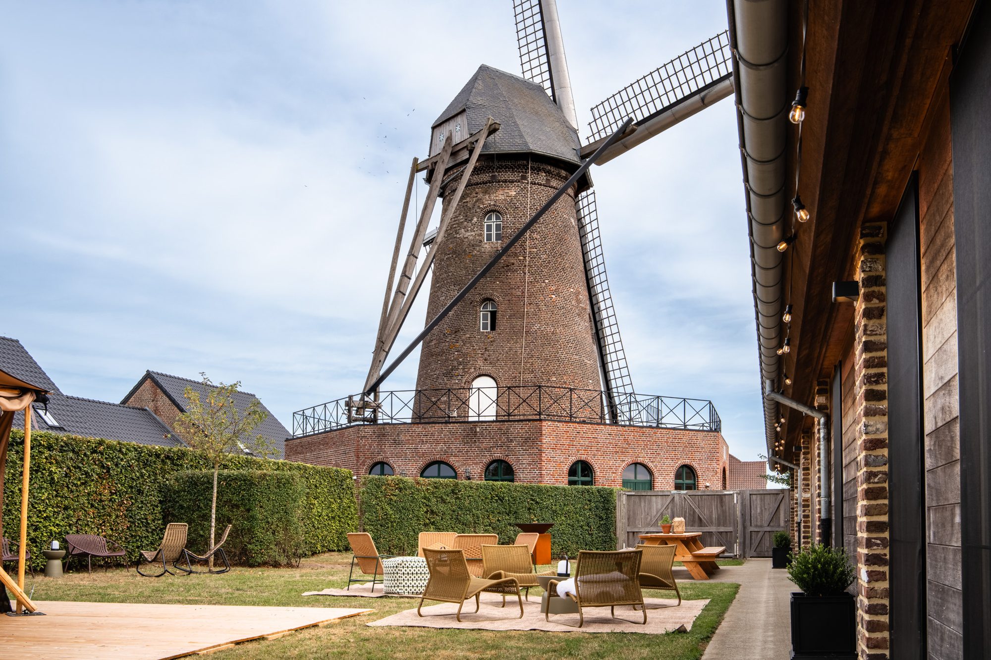 Windmolen De Hoop — Windmolen De Hoop torent boven het omheinde terras met loungestoelen bij de schuur